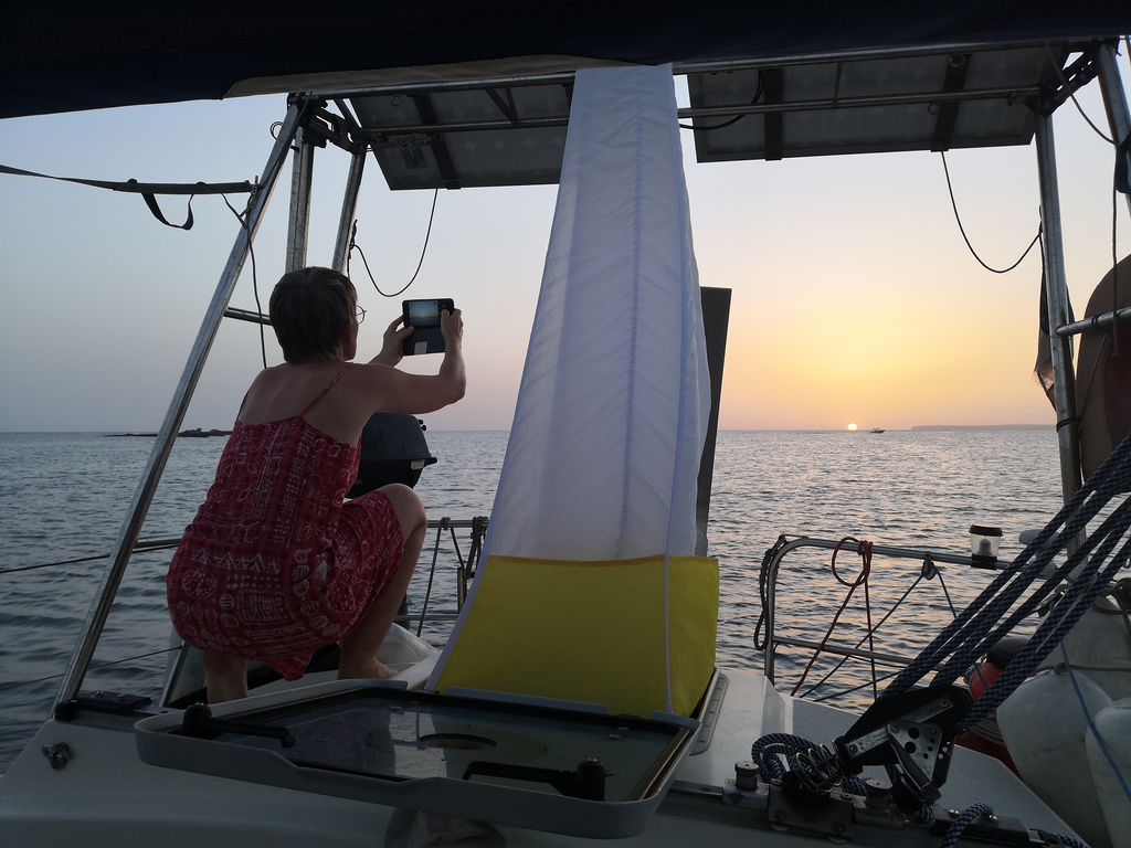 Sophie accropie à l'arriere du bateau pour prendre en photo le couché de soleil